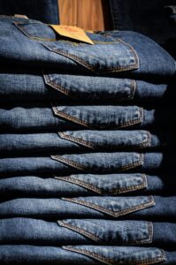 Pilha de calças jeans de tecido denim. Terceirização de jeans, modelagem especializada e beneficiamento têxtil.