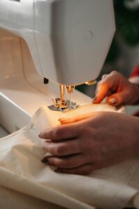 Detailed view of sewing process with hands guiding fabric on a machine.