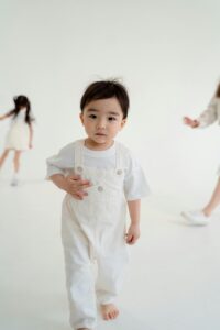 Bebê pequeno em roupa branca básica. Produção de peças para recém-nascidos, terceirização de enxoval e itens básicos.