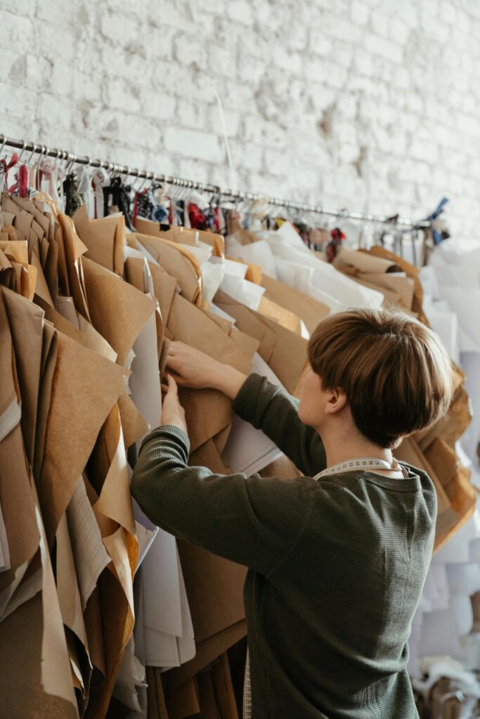 A young woman arranges sewing patterns in a creative workshop. Ideal for fashion and design themes.